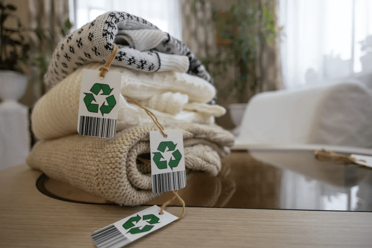 Folded clothes with recycling tags on table.