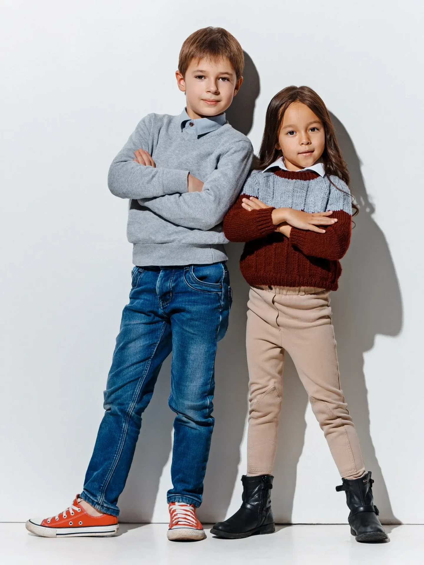 Two kids posing confidently against white background.