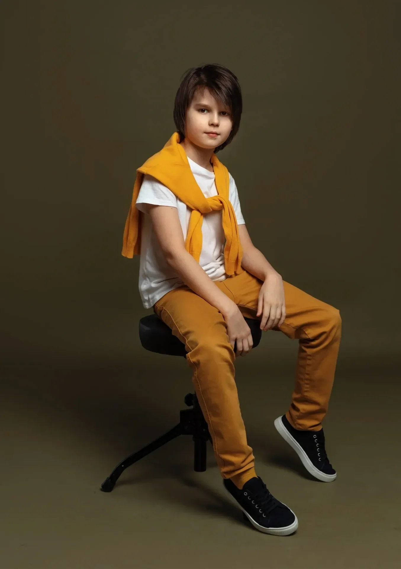 Child sitting on stool, casual outfit.